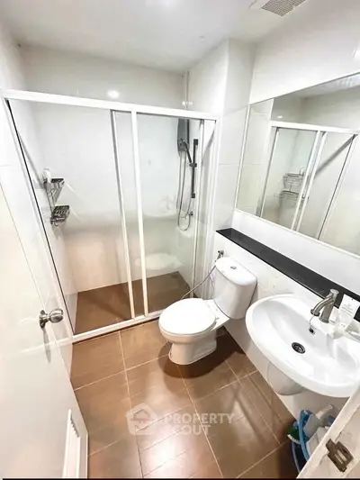 Modern bathroom with glass shower enclosure and sleek fixtures in a contemporary apartment.