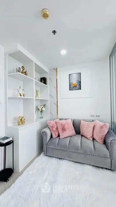 Chic modern living room with plush gray sofa and elegant white shelving unit.