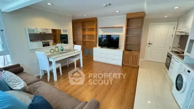 Modern living room with open kitchen, featuring hardwood floors and stylish furniture.