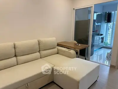 Modern living room with cozy beige sofa and sliding glass doors leading to a sleek kitchen.