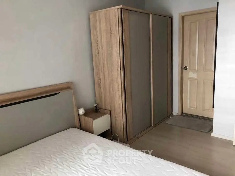 Cozy bedroom with wooden wardrobe and minimalist decor, perfect for relaxation.