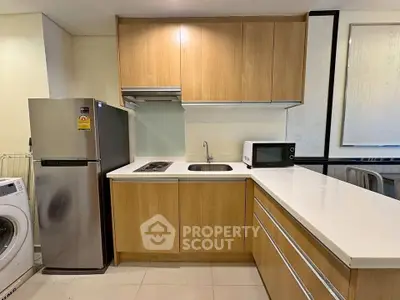 Modern kitchen with wooden cabinets, stainless steel fridge, and washing machine