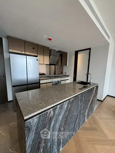 Modern kitchen with sleek marble island and stainless steel appliances in luxury apartment.