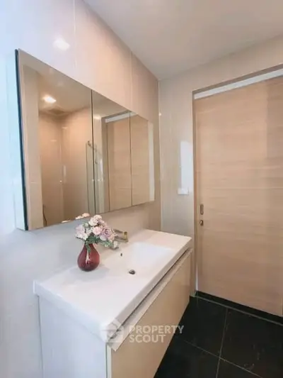 Modern bathroom with sleek vanity and large mirror in contemporary apartment.