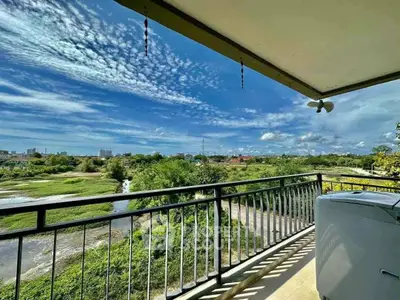 Stunning balcony view with lush greenery and city skyline under a vibrant sky.