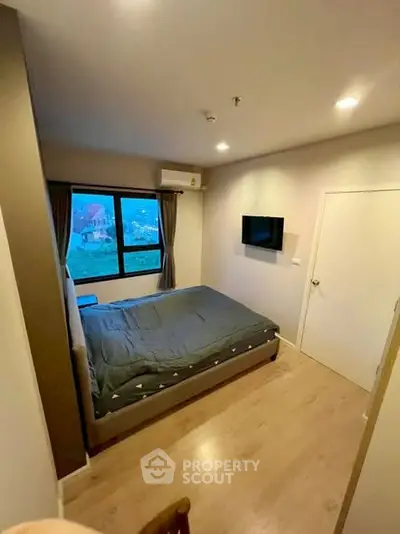 Cozy bedroom with modern decor and large window offering natural light.