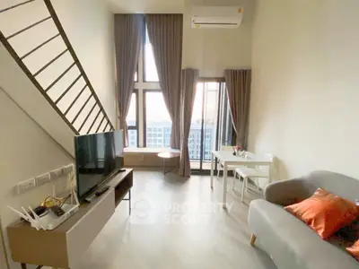 Modern living room with high ceilings, large windows, and stylish furniture in a bright apartment.