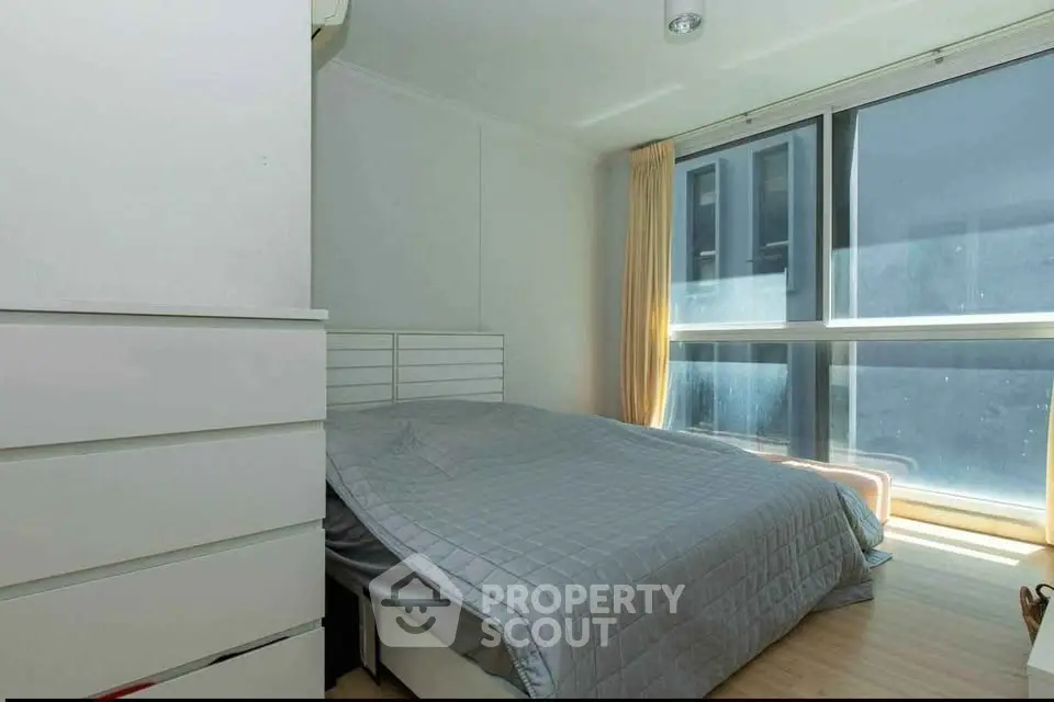 Bright and cozy bedroom with large window and modern furnishings.