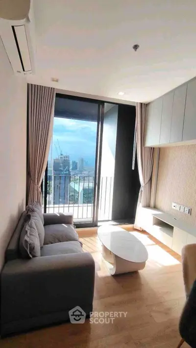 Modern living room with large window and city view, featuring sleek furniture and elegant decor.