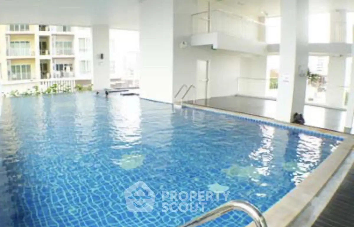 Luxurious indoor pool area with modern design and ample natural light in a high-end residential complex.