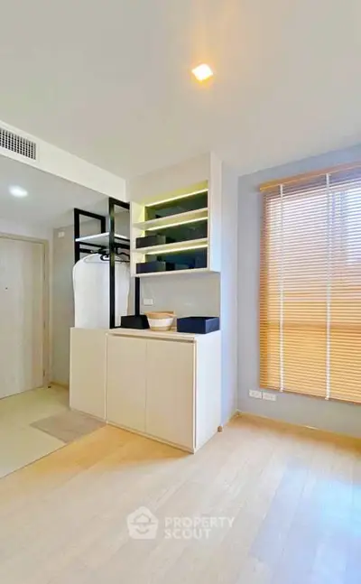 Modern bedroom with sleek storage and natural light, featuring minimalist design and warm wooden flooring.