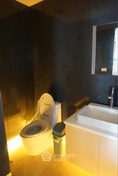Modern bathroom with sleek design and ambient lighting, featuring a stylish sink and toilet.