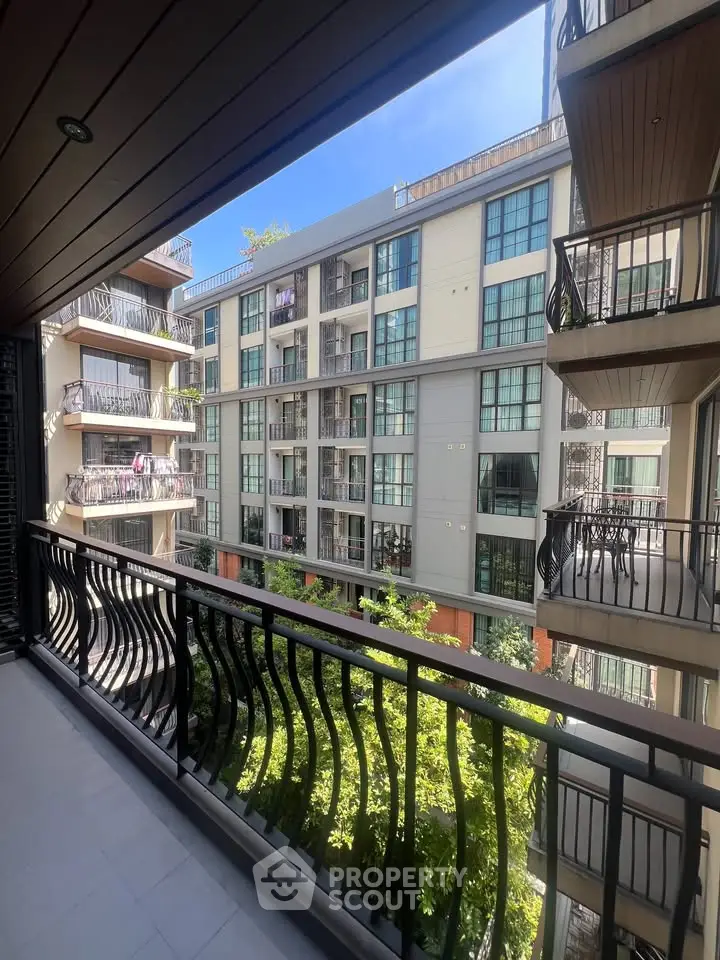 Modern apartment building view from balcony with stylish railings and lush greenery.