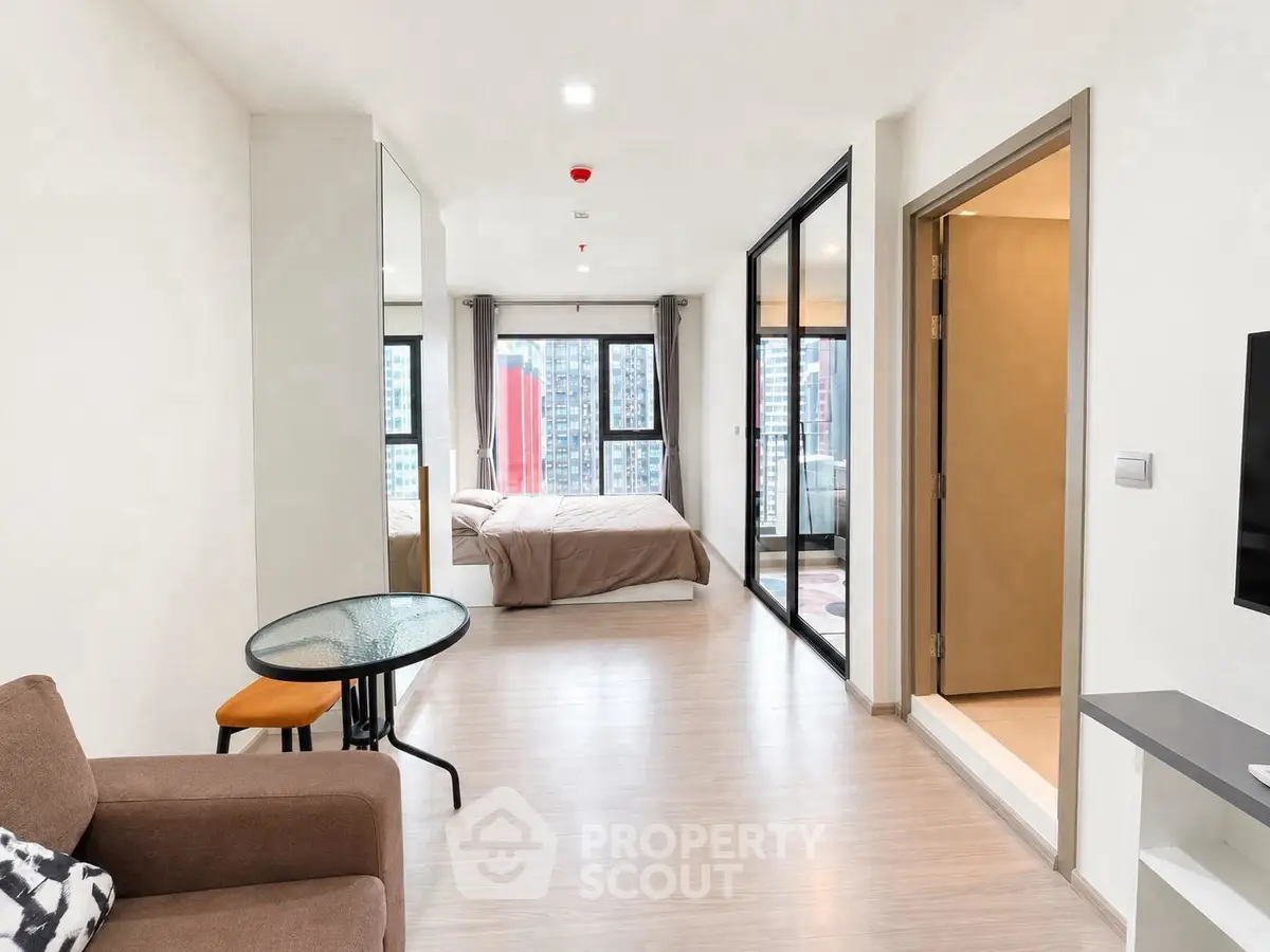 Modern open-plan apartment with spacious living area and bedroom, featuring large windows and city views.