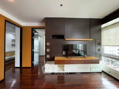 Modern living room with sleek wooden floors and built-in TV unit, offering a stylish urban view.