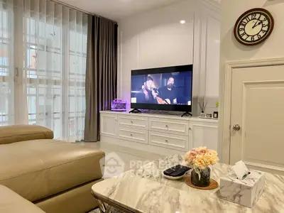 Elegant living room with modern decor, featuring a large TV, plush seating, and stylish marble coffee table.