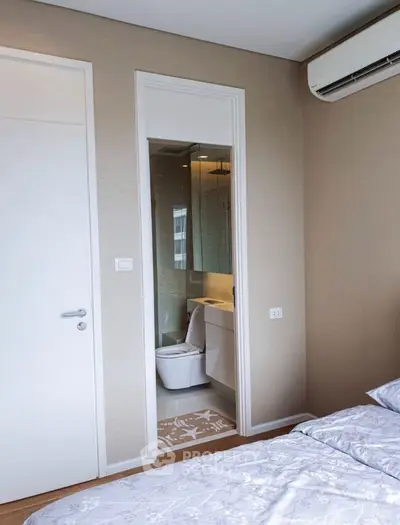 Modern bedroom with ensuite bathroom and air conditioning in a stylish apartment.