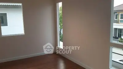 Spacious empty room with large windows and wooden flooring