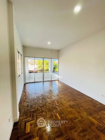 Spacious living room with polished wooden floors and large windows for natural light.