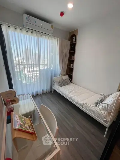 Modern small bedroom with city view, featuring a single bed, desk, and floor-to-ceiling window.