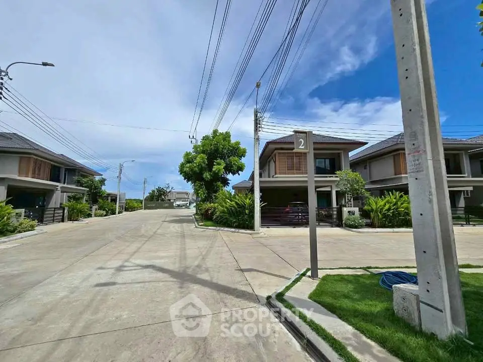 Modern residential neighborhood with contemporary houses and lush greenery under a clear blue sky.
