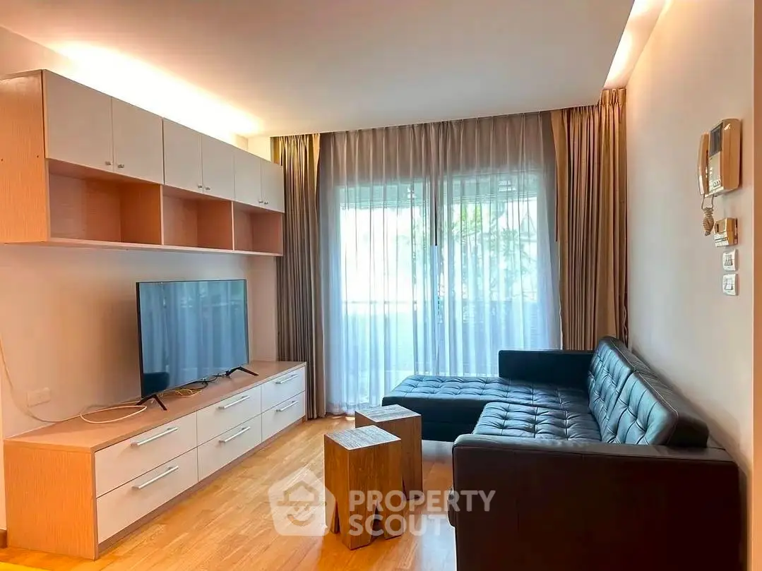 Modern living room with sleek furniture and natural light, featuring a stylish TV unit and cozy seating area.