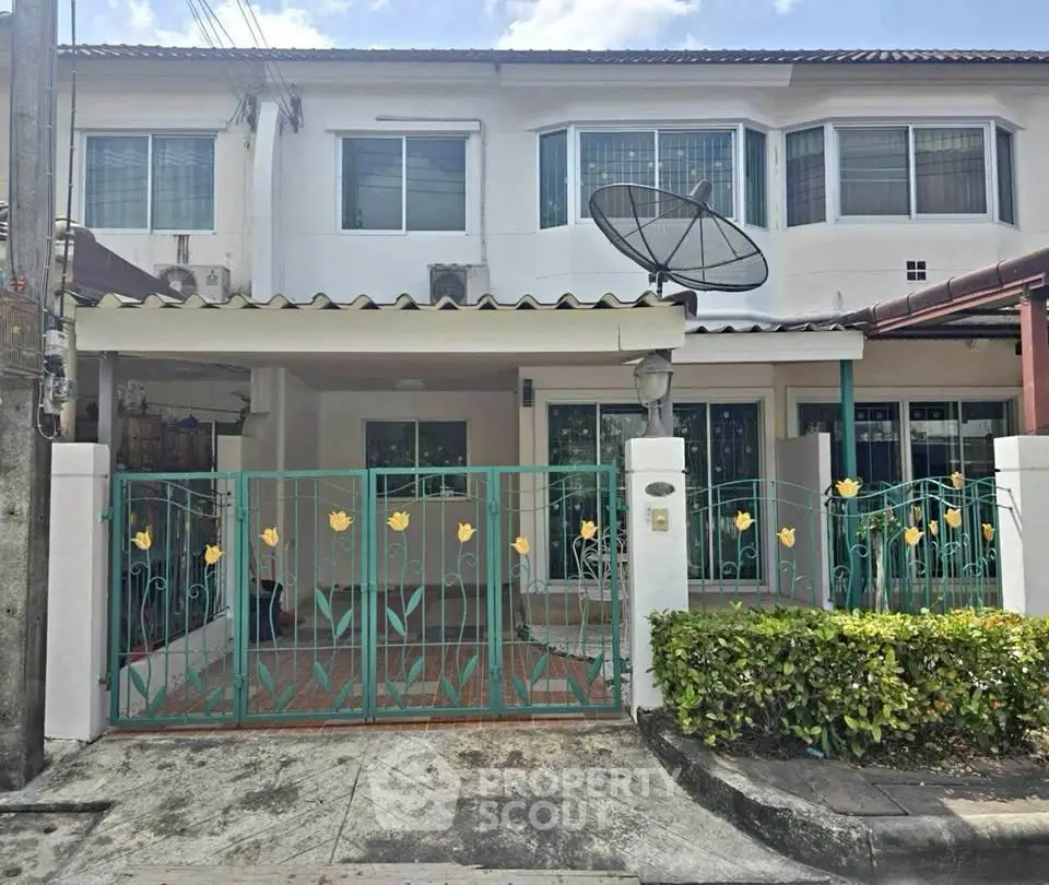 Charming two-story townhouse with decorative gate and satellite dish, perfect for modern living.