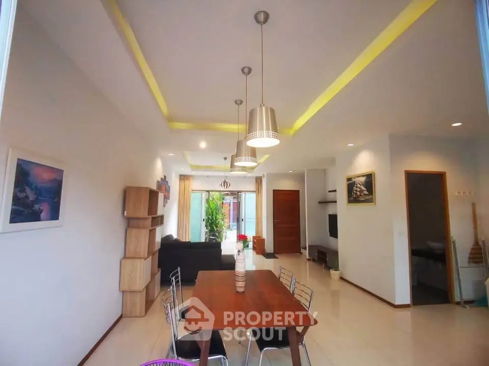 Spacious modern living room with elegant dining area and stylish lighting fixtures.