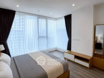 Modern bedroom with large windows and elegant decor in a high-rise apartment.