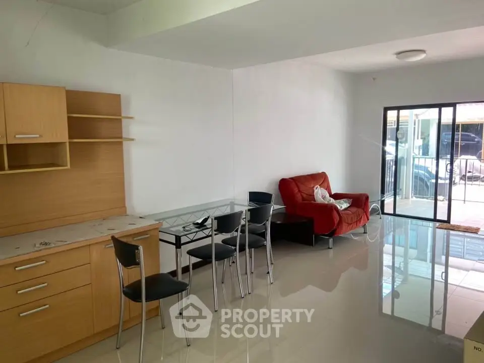 Spacious living room with modern furniture and glass doors leading to a balcony.