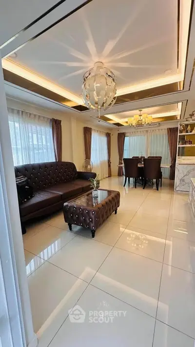 Luxurious living room with elegant decor and dining area, featuring plush seating and modern lighting.