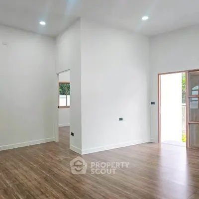 Spacious modern living room with wooden flooring and ample natural light.