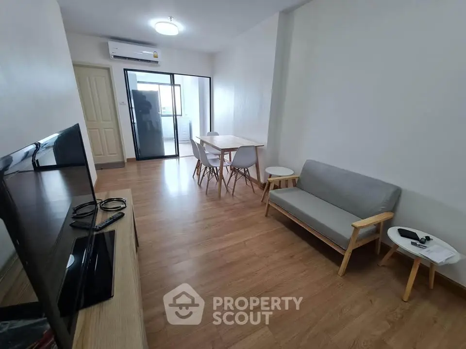 Modern living room with wooden flooring, cozy sofa, and dining area in a bright apartment.