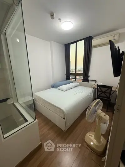 Cozy bedroom with city view, featuring modern furnishings and natural light.