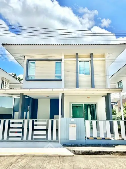 Modern two-story house with sleek design and gated entrance in sunny neighborhood.