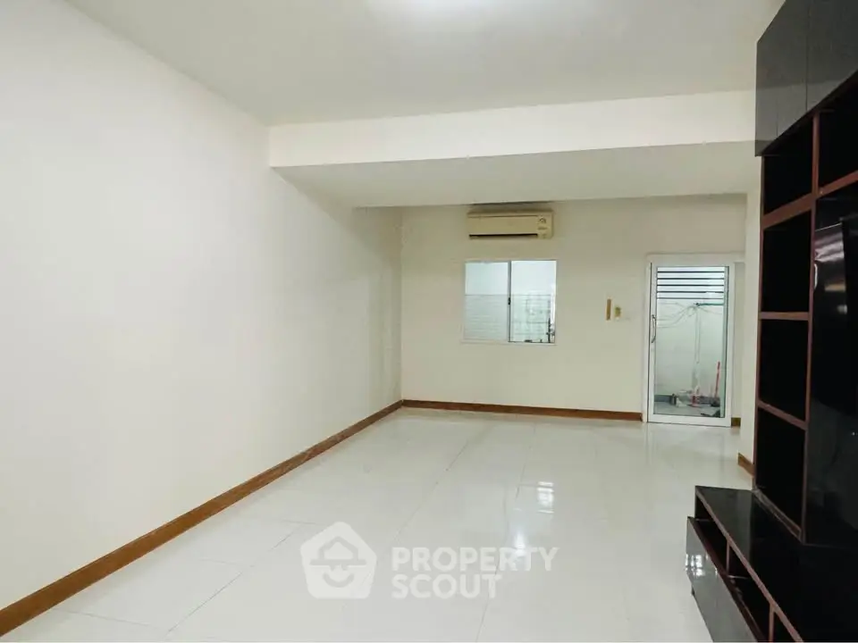 Spacious empty living room with sleek tile flooring and built-in shelving unit.