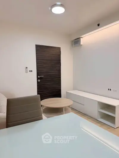 Modern living room with sleek furniture and minimalist design, featuring a wooden door and stylish lighting.