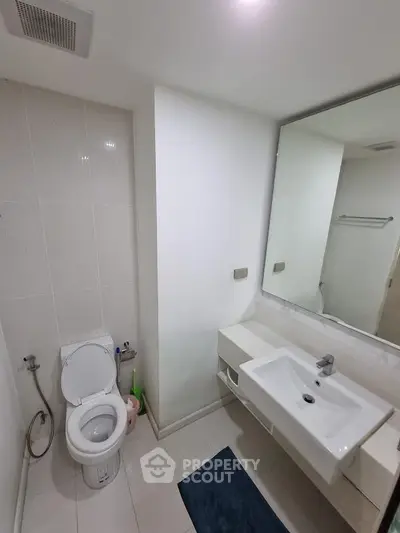 Modern bathroom with sleek fixtures and large mirror in a minimalist design.