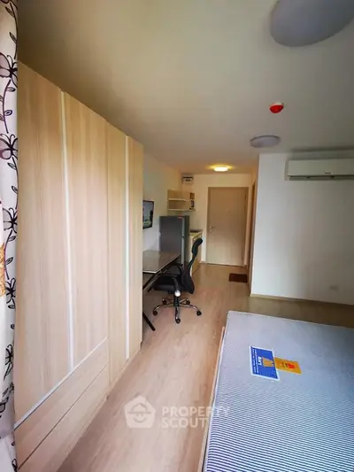 Modern bedroom with study area and wooden wardrobe in a cozy apartment.