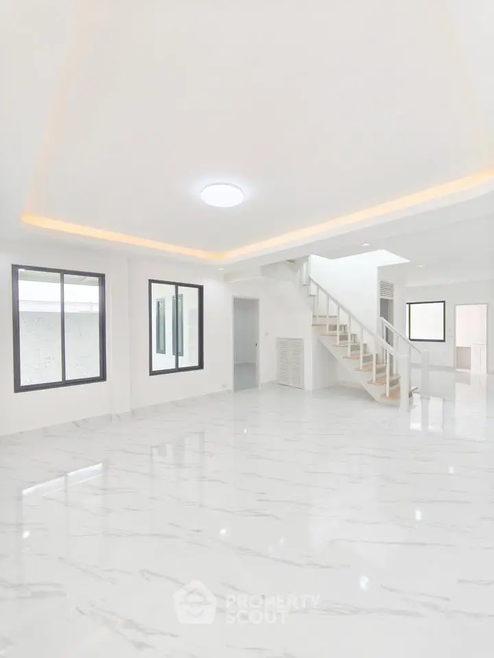 Spacious modern living room with elegant staircase and marble flooring