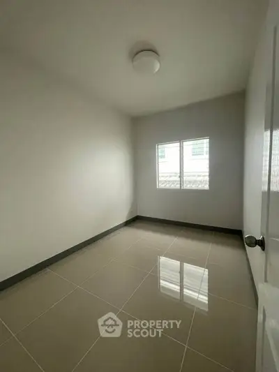 Spacious empty room with tiled flooring and natural light from window