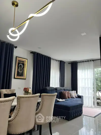 Elegant living room with modern chandelier and plush seating, featuring floor-to-ceiling windows and stylish decor.