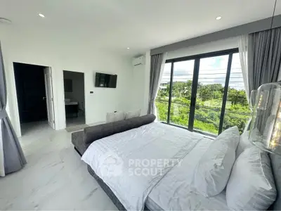 Spacious bedroom with large windows offering lush green views, modern decor, and natural light.