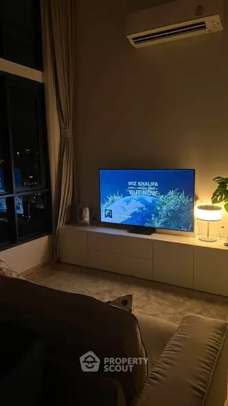 Cozy living room with modern decor and ambient lighting, featuring a wall-mounted TV and air conditioning.
