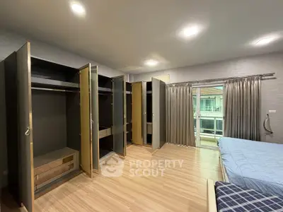 Spacious bedroom with modern wardrobes and large window view