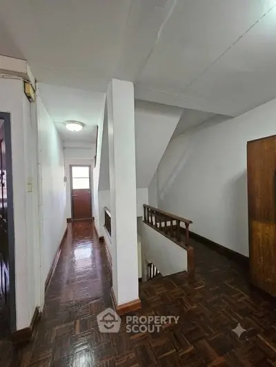 Spacious hallway with wooden flooring and staircase in a residential property.