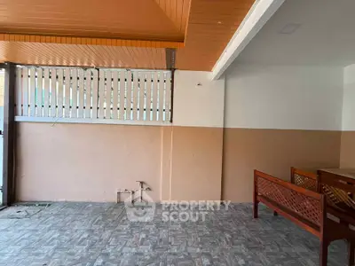Spacious covered patio with tiled flooring and wooden seating area.