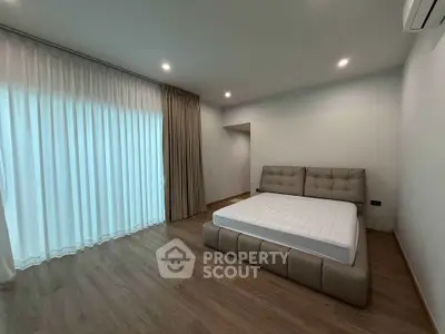 Spacious modern bedroom with elegant flooring and stylish bed frame, perfect for comfort and relaxation.