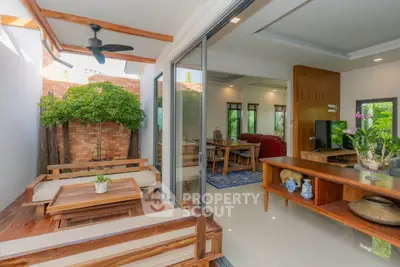 Spacious open-plan living room with natural light and modern wooden furniture, perfect for relaxation.