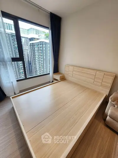 Modern bedroom with wooden flooring and large window offering city view